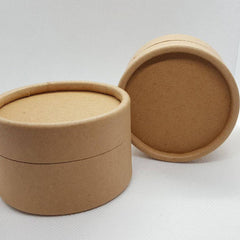 Side view of 25 minimalist kraft skincare jars with matte black lids and clean labeling, stacked neatly