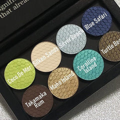 Eyeshadow palette with various colors and textures, including green, blue, brown, and gold shades with text labels