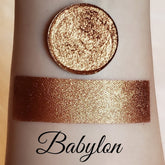 Eyeshadow pigment swatch, bronze shimmer with Babylon text, applied on skin