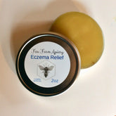 Skin care eczema relief product with yellow balm, metal tin, and Fox Farm Apiary label