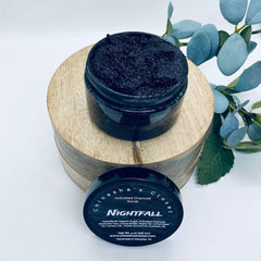 Activated charcoal scrub in black jar with wood base, "Chinesha's Closet" text visible, Nightfall label on lid