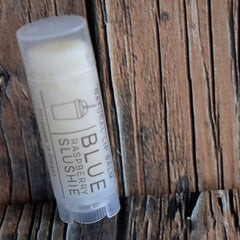 Lip balm tube, white plastic, blue text, on wood grain background