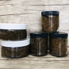 Emulsified coffee scrub in clear jars with black and white lids on wood grain background