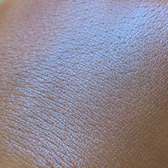 Close-up of fingertips applying vibrant blue eye shadow pigment to eyelid for a bold makeup look