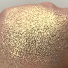Gold shimmer swatch on skin, showing textured surface and light reflection