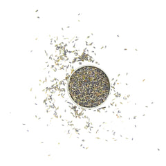 Lavender buds in a silver bowl, scattered purple and green dried flowers on white background