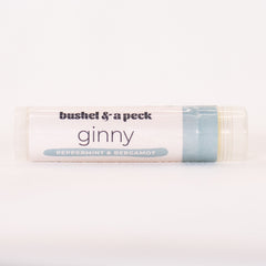 Lip balm tube with white label, light blue accent, and "Bushel & a Peck" text