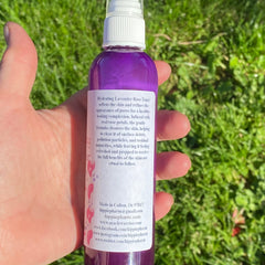 Purple toner bottle with white cap and label, held in hand against green grass background
