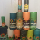 Skin care products in various colors with Sunmade Naturals labels, stacked in cylindrical containers