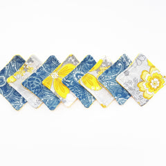 Coasters with floral and paisley patterns in blue, yellow, and gray with yellow trim