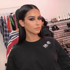 Black sweatshirt with white Japanese text, worn by woman with dark hair, in a studio setting