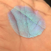 Eye shadow pigment, iridescent blue-green color, textured application on skin