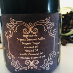 Coffee scrub jar with dark purple label, white floral design, and ingredient list visible