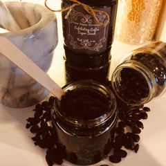 Exfoliating coffee sugar scrub in glass jars, dark brown color, with coffee beans scattered around