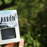 Charcoal skincare soap, black bar in white box, Oleozon branding visible, held in hand