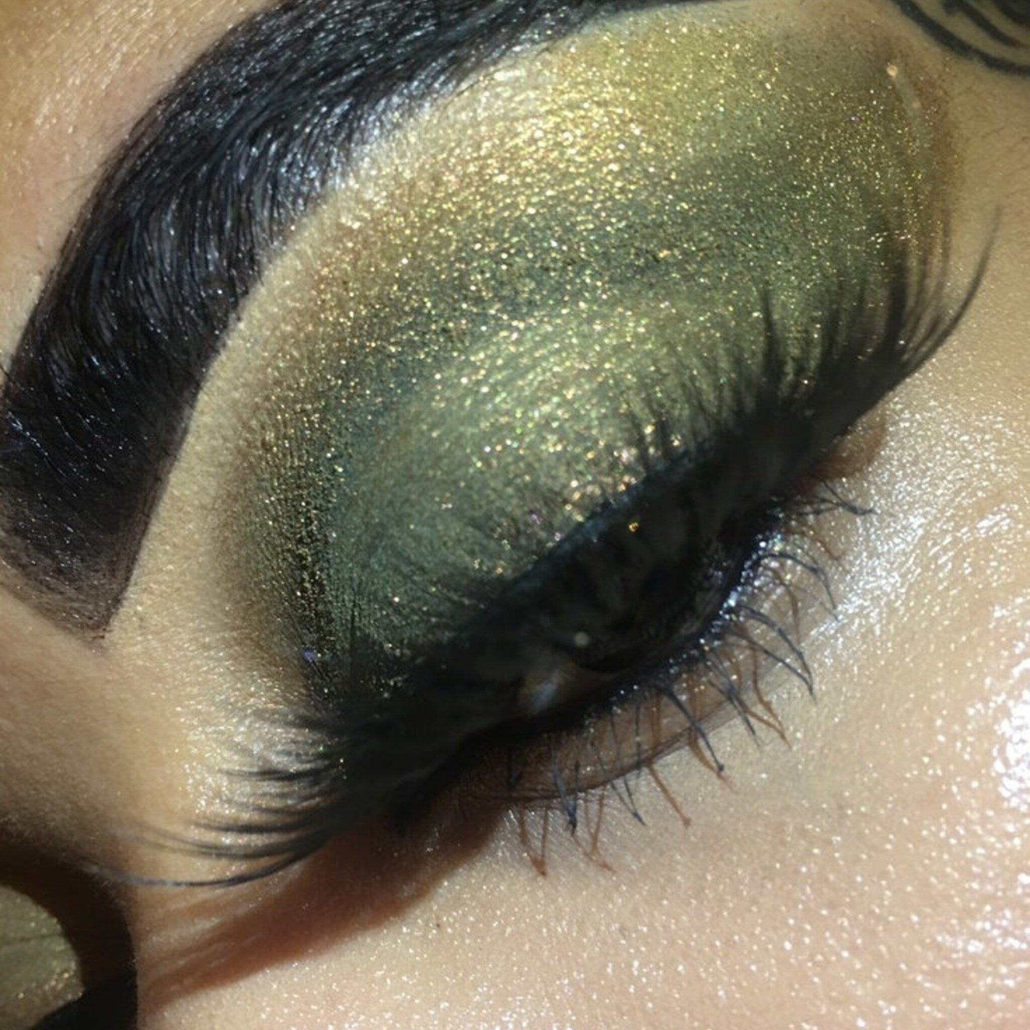 Shimmer eyeshadow in green and gold with glitter on eyelid, eye makeup application