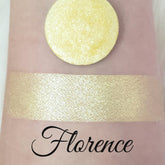 Eyeshadow swatch with gold shimmer and "Florence" text on skin