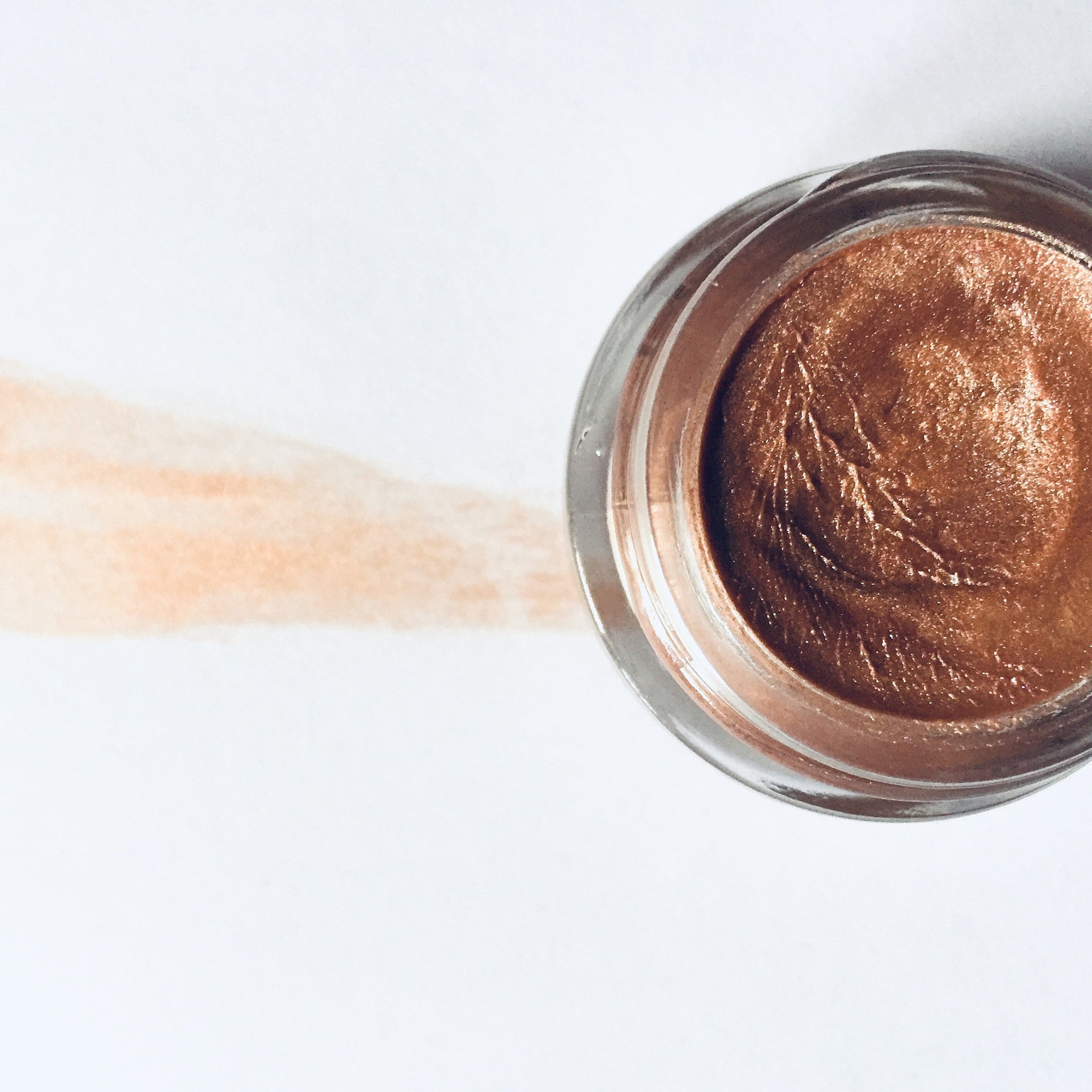 Lip & cheek stain rose gold pigment in clear glass jar with swatch on white background