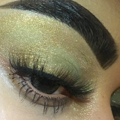 Eye makeup with gold glitter eyeshadow, dark lashes, and dark eyebrow detail