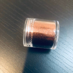 Close-up of matte black eye shadow with fine shimmer particles in compact palette