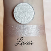 Eyeshadow shimmer pigment, silver pressed powder and swatch on skin, Luxor brand visible