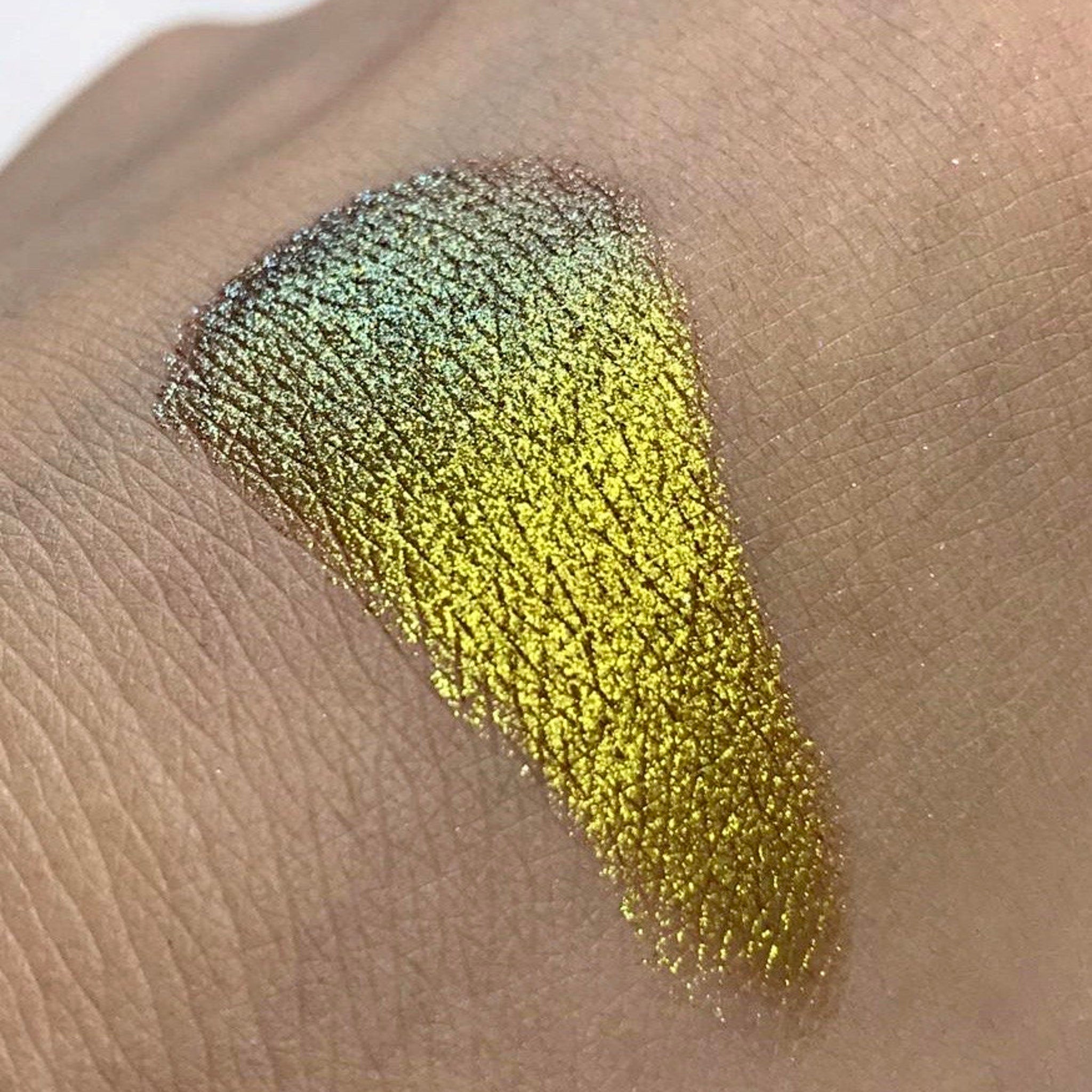 Eye makeup swatch of green and gold sparkle eyeshadow on skin