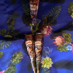 Close-up of natural brown henna cone with intricate mehndi design on skin, showcasing rich texture and warm tone