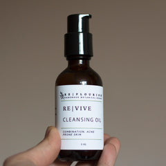Cleansing oil bottle with black pump, brown glass, and white label, REVIVE brand