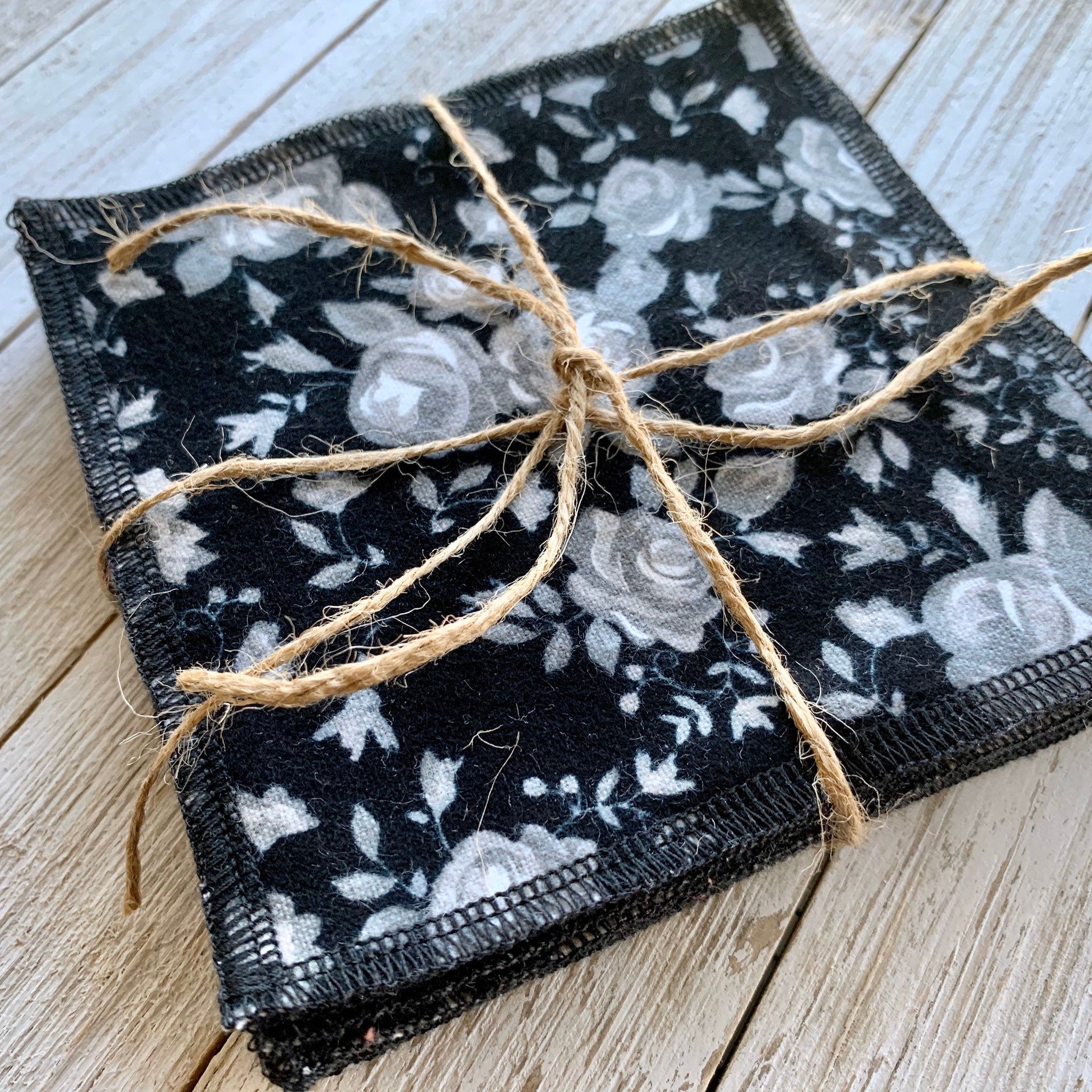 Makeup remover cloths, black floral pattern, tied with twine, on wood surface