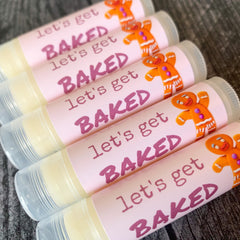 Lip balms with pink labels, gingerbread man design, and "Let's Get Baked" text visible