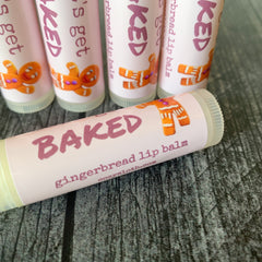 Gingerbread lip balm tubes with pink and white labels, orange gingerbread man, and "BAKED" text