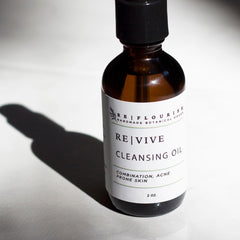 Cleansing oil bottle with brown glass, black cap, and white label, REVIVE brand visible