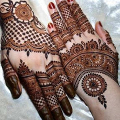 Close-up of natural brown henna cone being applied to hand in delicate swirling patterns for skincare benefits