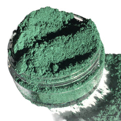 Green powder in a clear glass jar with a white background and shadow.