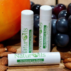 Lip balm tubes, white with green label, NaturOils brand, with fruit and nuts in background