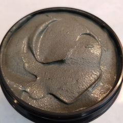 Black glass jar of activated charcoal and turmeric face mask with gold lid and minimalist label