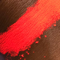 Close-up of vibrant red eyeshadow pigment with ultra-fine shimmer particles in compact pan