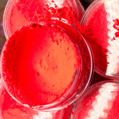 Hand applying vibrant red eyeshadow pigment with fingertip onto eyelid for bold makeup look