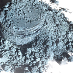 Powdered pigment, blue-gray powder, in a clear jar, close-up view of loose material