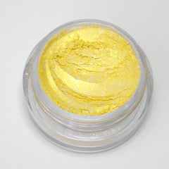 Close-up of loose mica pigment in golden shimmer with fine sparkling particles and soft powdery texture