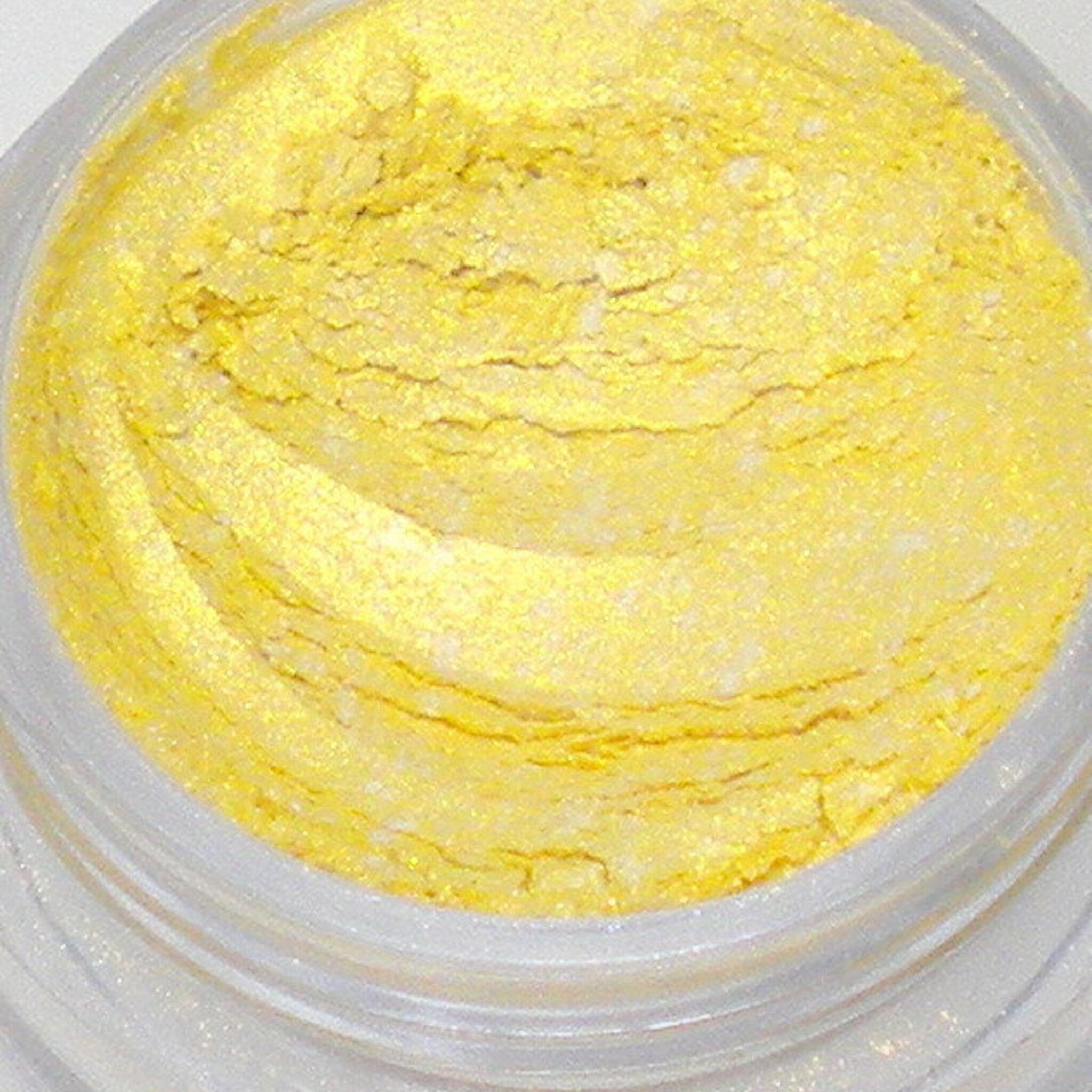 Close-up of loose mica eyeshadow powder in bright sunshine yellow with shimmer particles