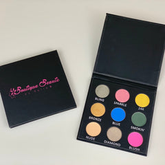 Open rectangular palette displaying nine vibrant eyeshadow shades in matte and shimmer finishes with a mirror