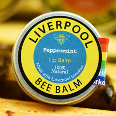 Lip balm tin with yellow and blue label, silver rim, and Liverpool Bee Balm text