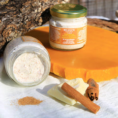 Facial scrub jars with beige cream, visible brand label, and gold lids on a white cloth