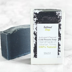 Charcoal soap bar, dark gray, textured, with Tailored Soap label in white packaging