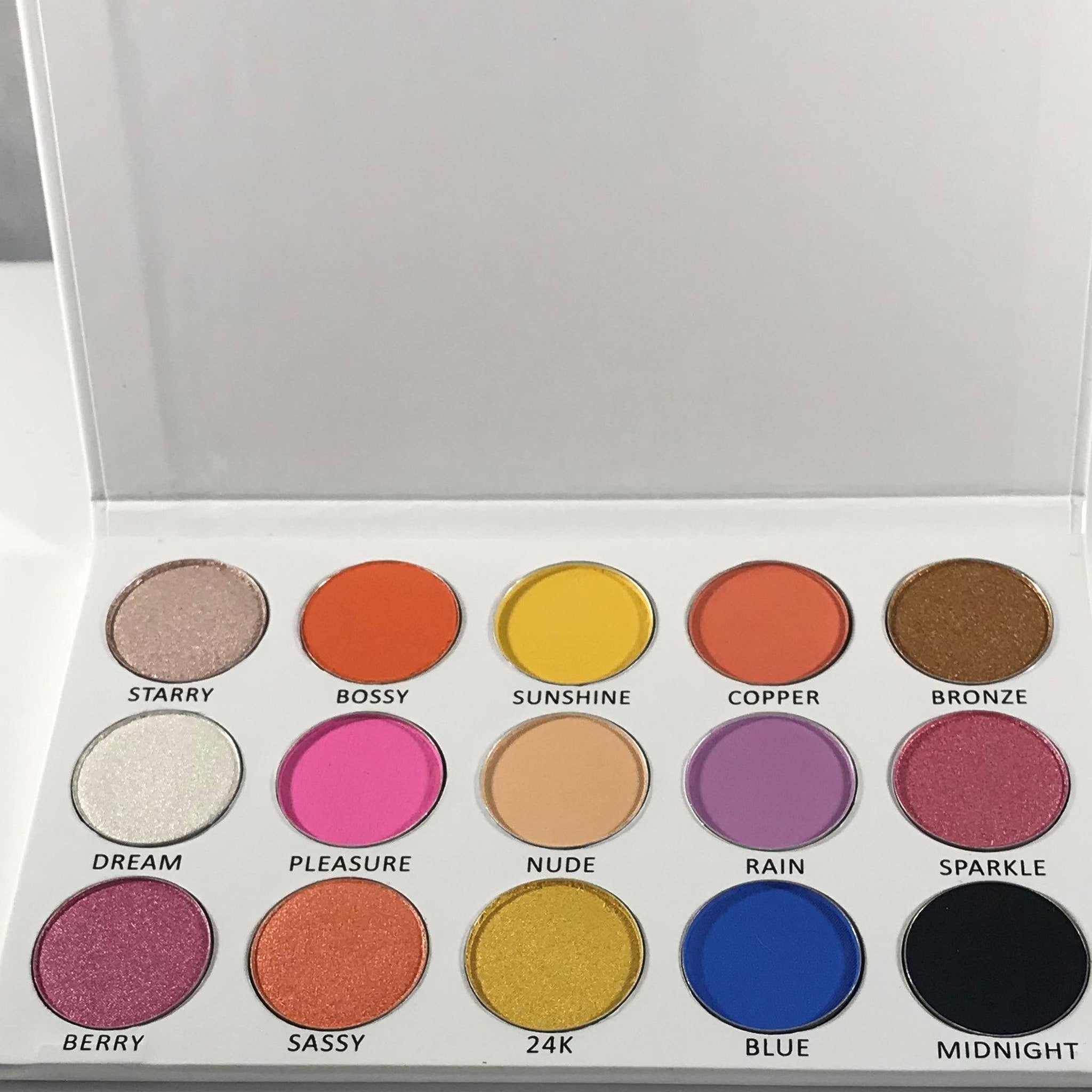 Open rectangular palette displaying 15 vibrant tropical eyeshadows in matte and shimmer finishes with mirror inside