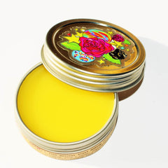 Balm jar with yellow balm, silver metal container, and colorful lid design