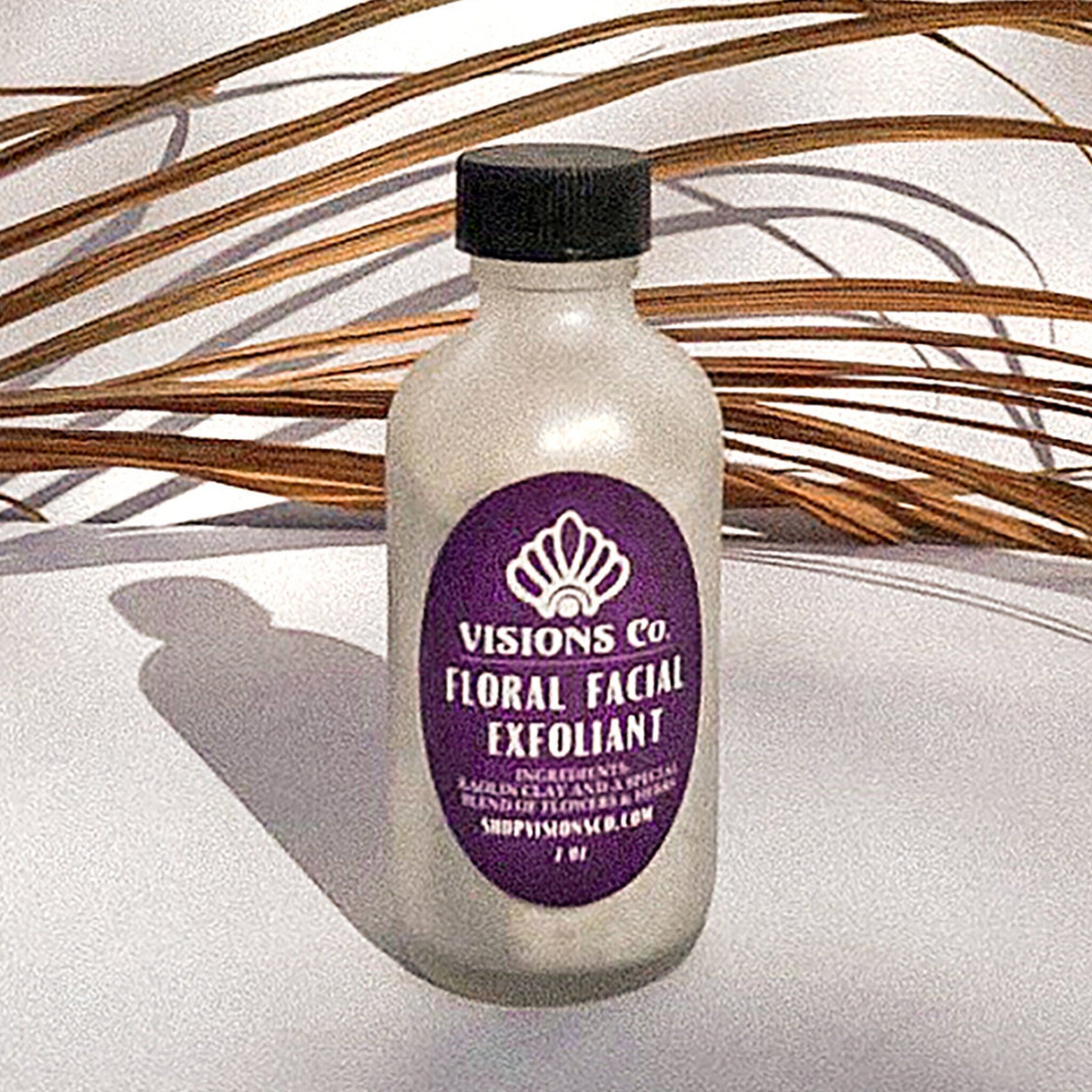 Floral facial exfoliant bottle with purple label, black cap, and Visions Co. text
