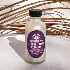 Floral facial exfoliant bottle with purple label, black cap, and Visions Co. text