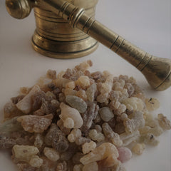 Frankincense resin with beige, brown, and green hues, and a brass mortar and pestle in the background
